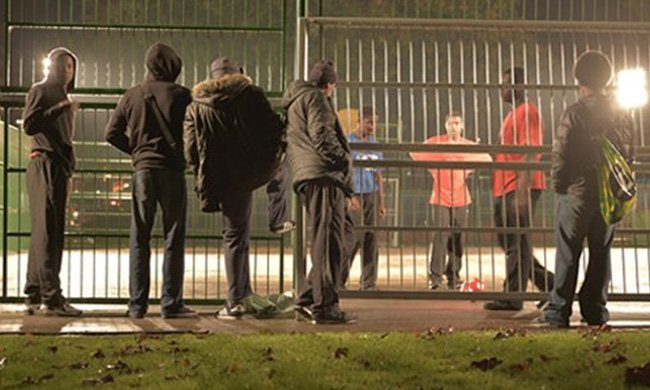 young people standing by gated football pitch