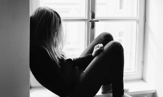 young person sitting by a window