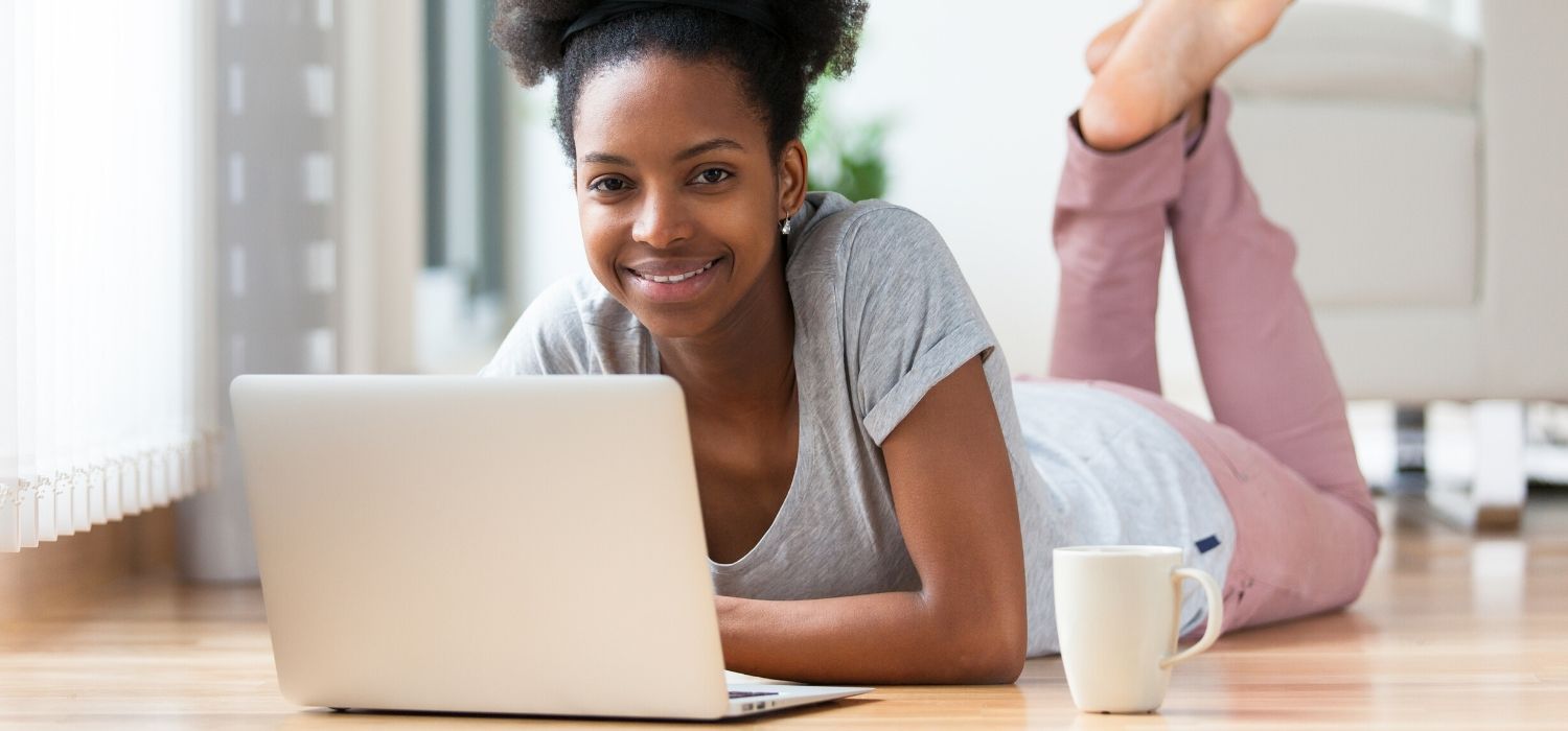 young person with laptop and coffee on the floor